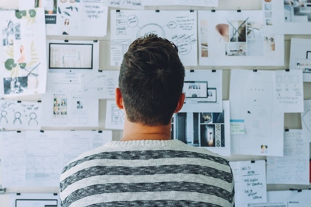 A person looking at a board with business plans symbolizing reasons why your startup business fails.