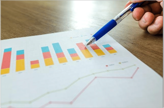 A person pointing at a paper with metrics with a blue pen